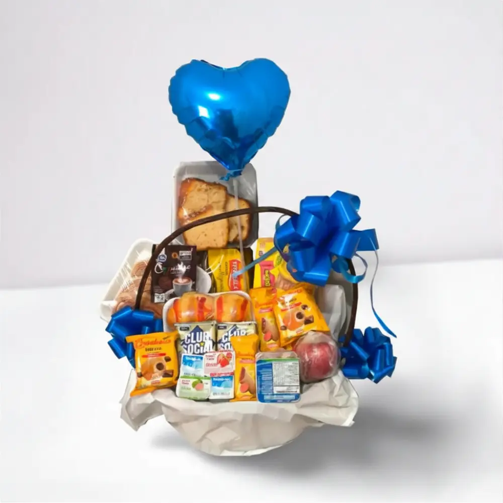 Cesta de café da manhã infantil masculino com chocolates, biscoitos, itens doces e balão azul.