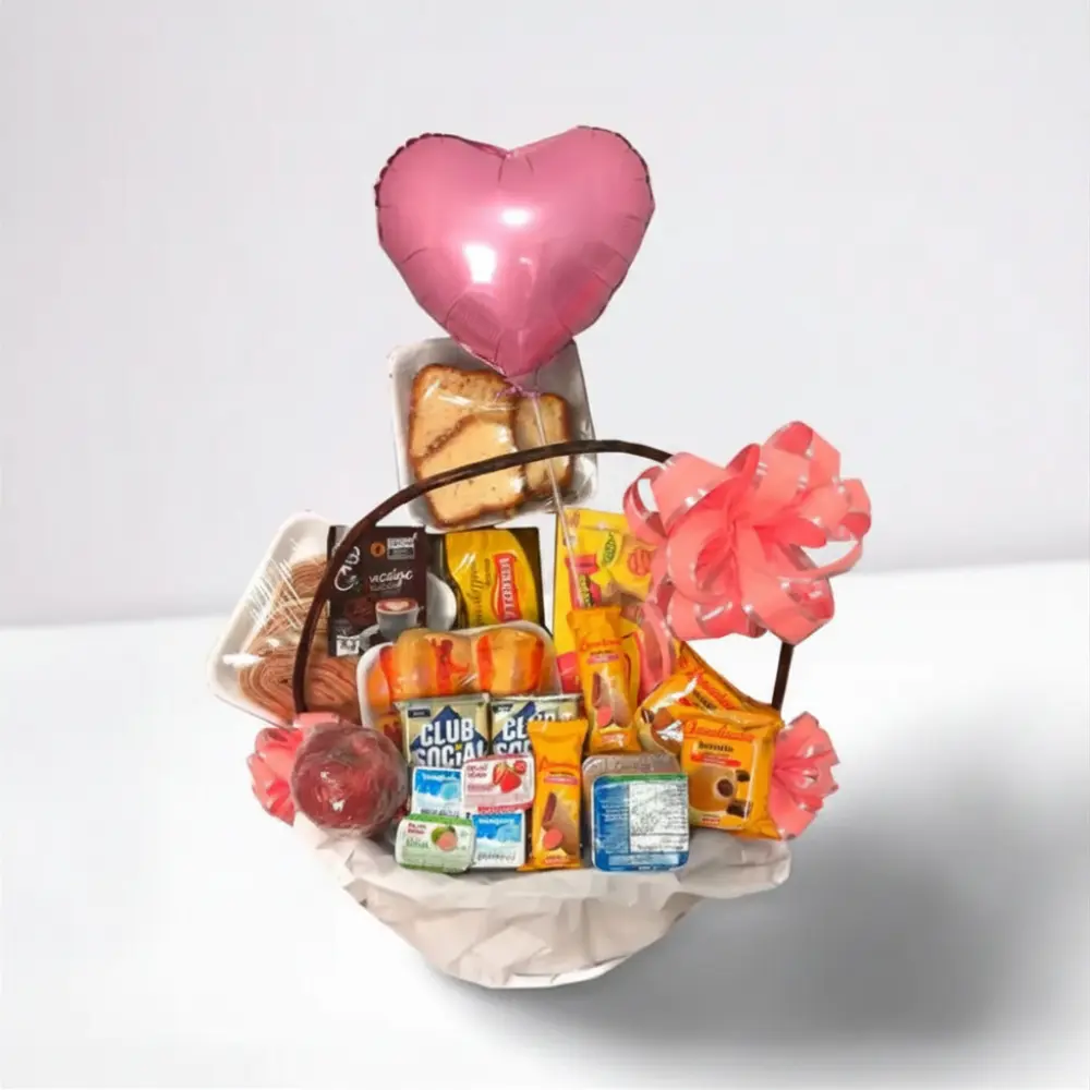 Cesta de Café da Manhã Infantil Menina com balão em formato de coração, chocolates, biscoitos, suco e itens decorativos em cesta rústica.